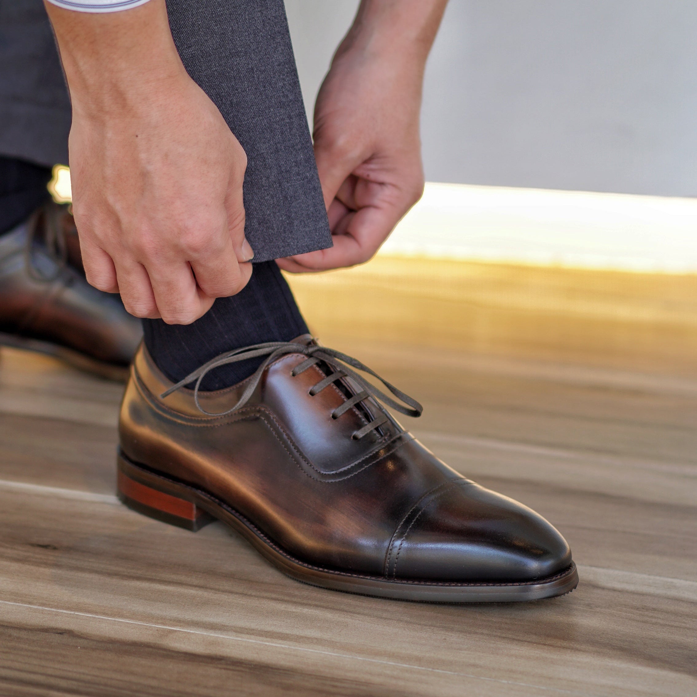 Pair of brown leather Oxford shoes with a sleek silhouette and classic lace-up style, displayed on blue fabric